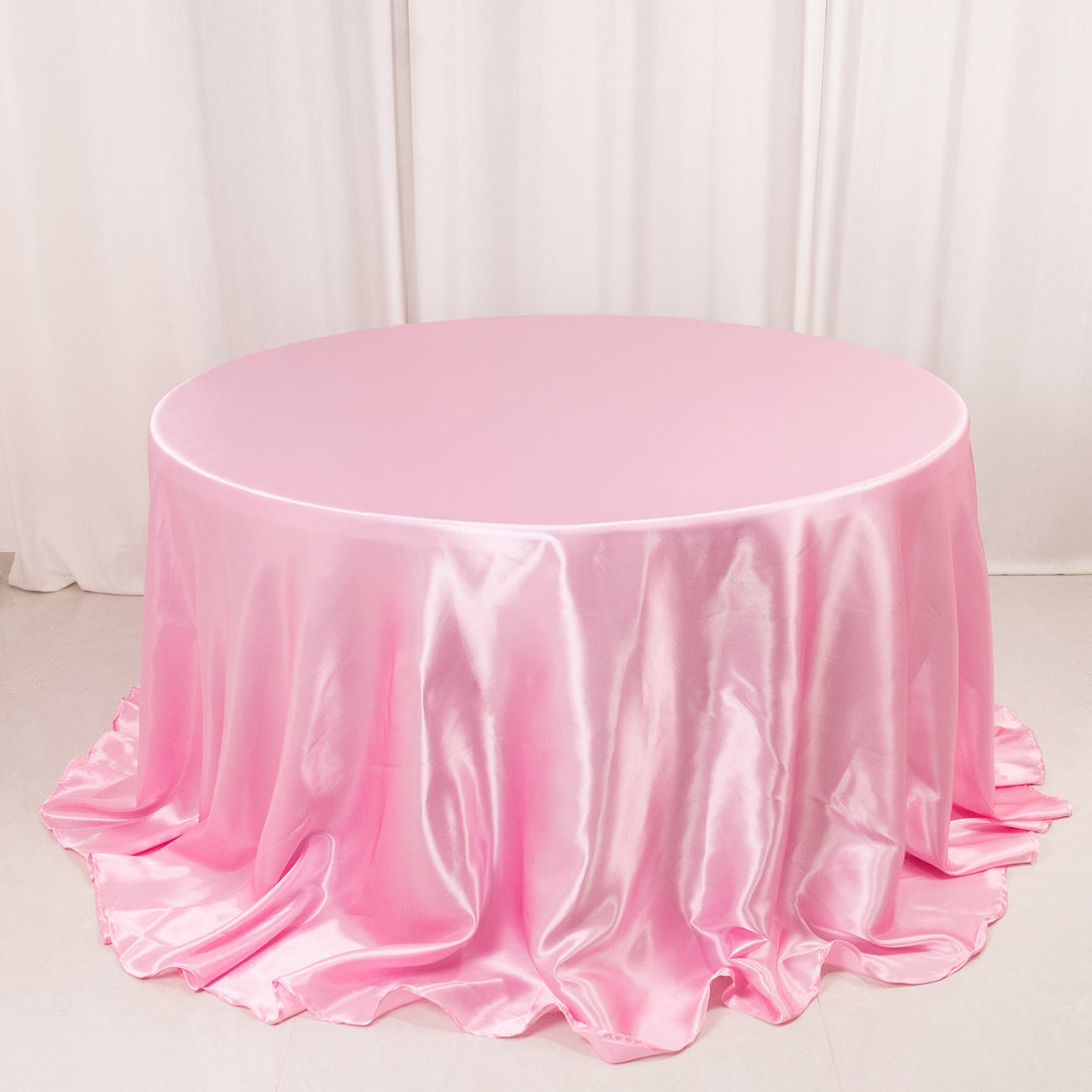 Round pink satin tablecloth with elegant draping.