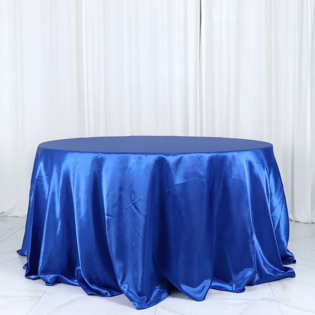 Round blue satin tablecloth draping elegantly on a plain backdrop.
