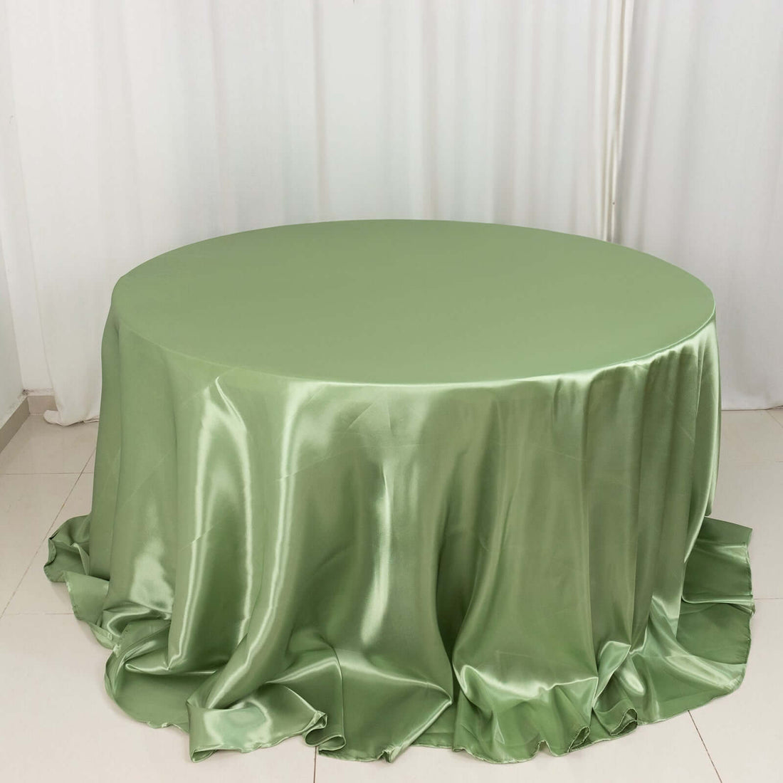 Round satin tablecloth in soft green, elegantly draped.