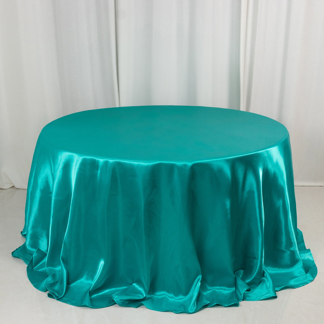 Teal satin tablecloth draped elegantly over a round table.