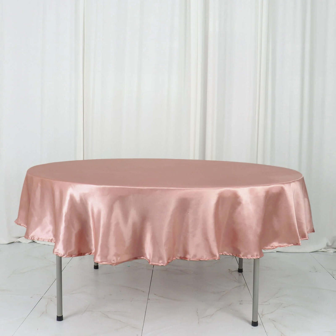 Round satin tablecloth in soft pink on a white backdrop.