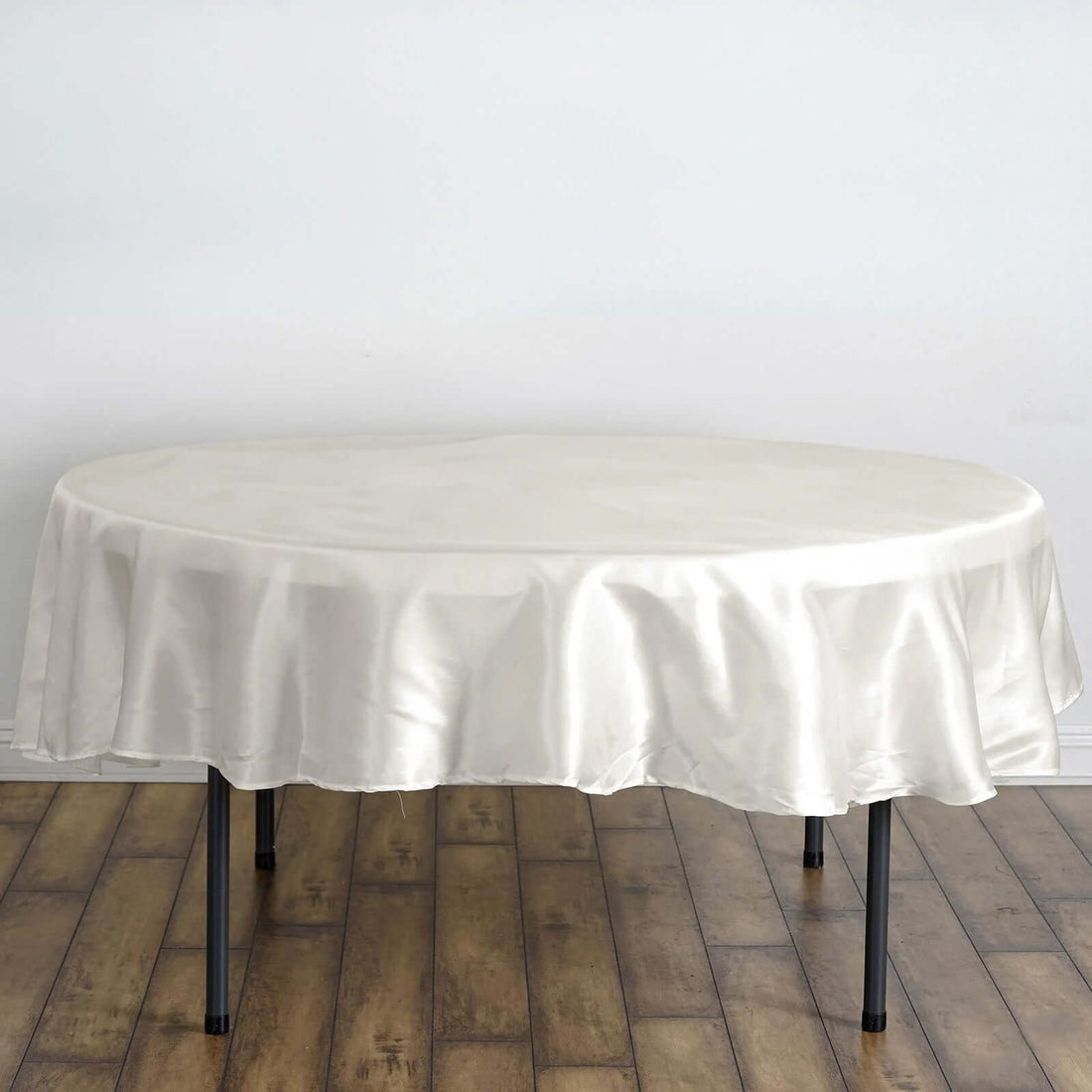 Round satin tablecloth in ivory draped over a table