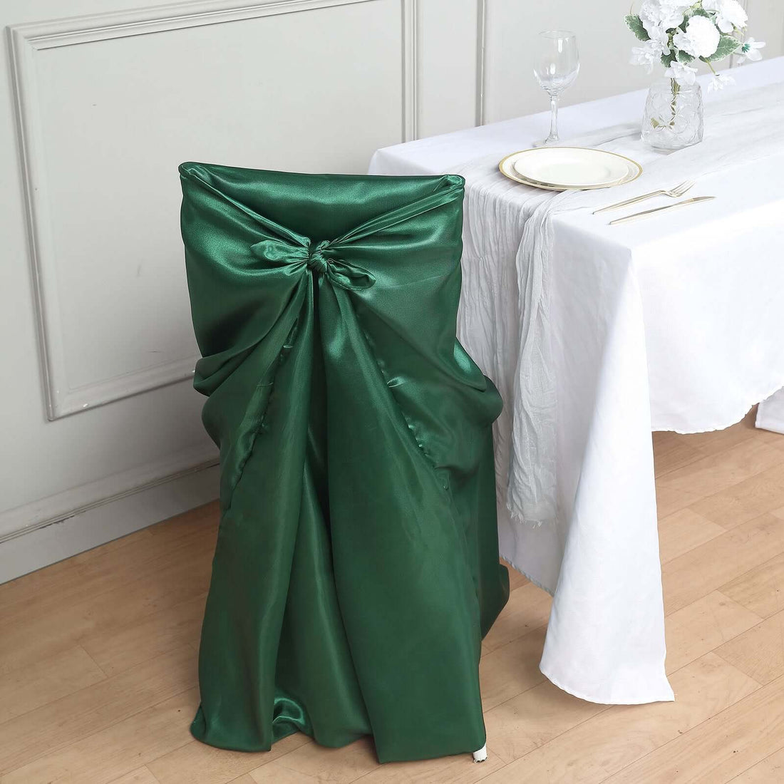 Green satin chair cover draped elegantly over a dining chair.