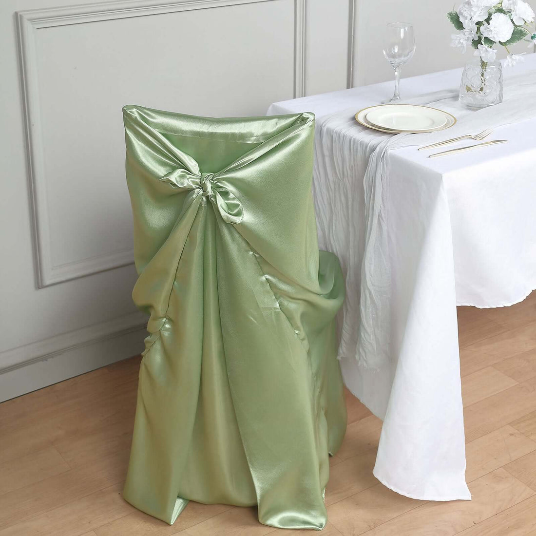Green satin chair cover with bow detail for elegant dining setups.
