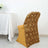 Elegant gold floral chair cover draped over a chair at a dining table.