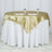 Gold satin tablecloth draped over a round table with glassware.