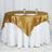 Gold satin tablecloth draped elegantly on a round table with plates and glasses.