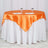 Orange satin tablecloth on a round table with two glasses.