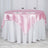 Round table with pink satin tablecloth and white overlay, set for dining.
