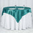Teal satin tablecloth draped over a white table with plates and glasses