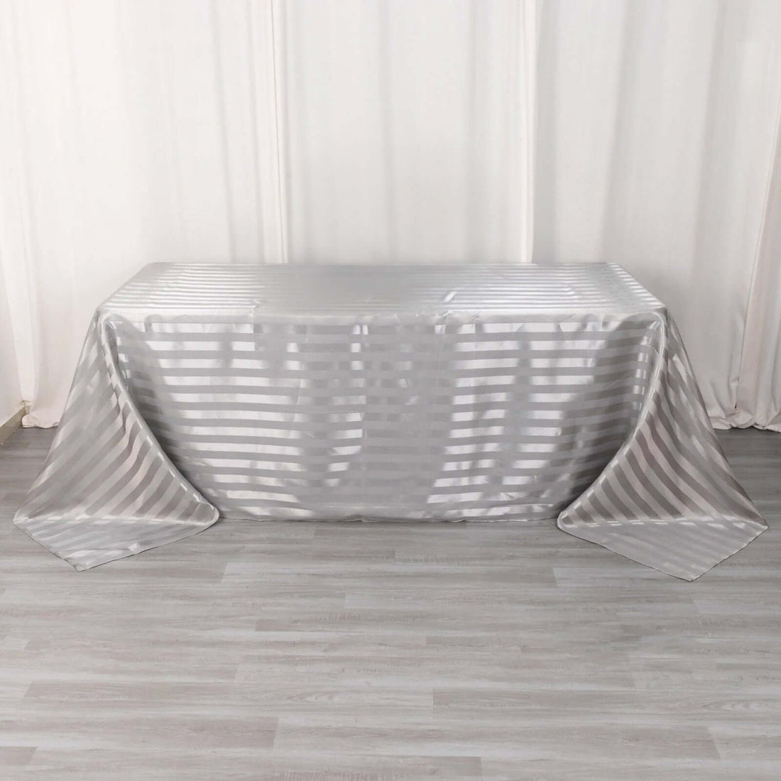 Silver striped tablecloth draped over a table in a studio setting.