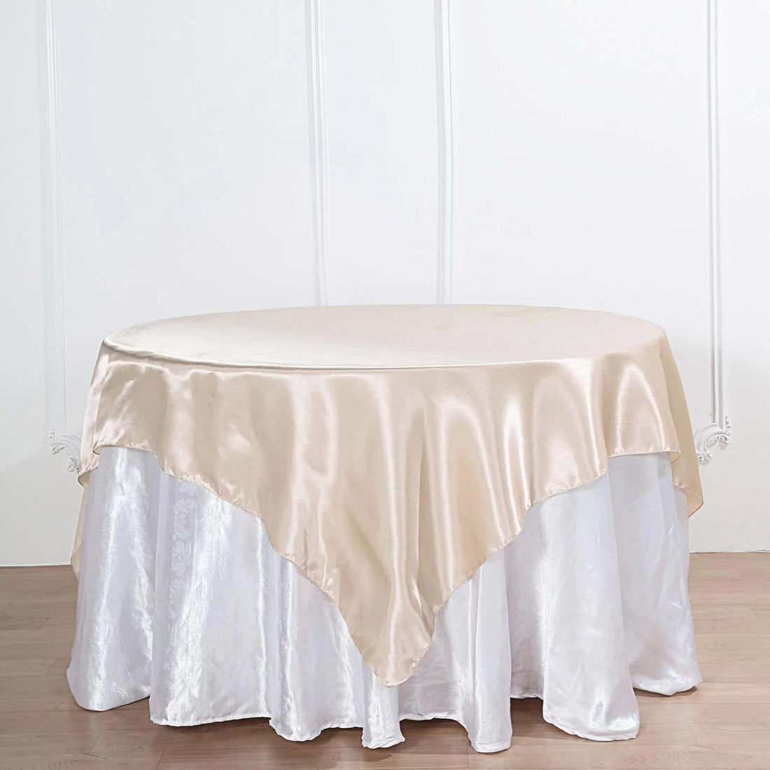 Round table with a satin beige tablecloth.