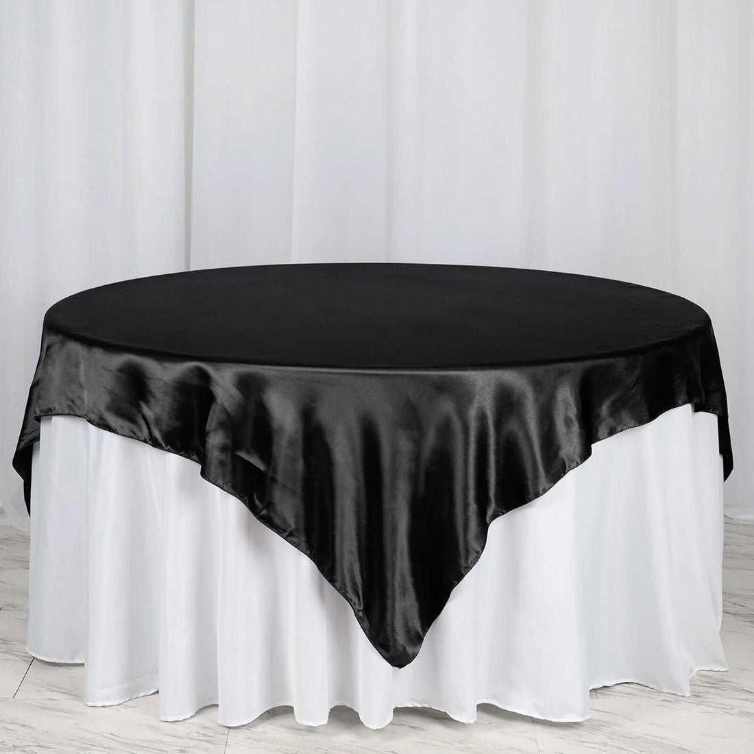 Black satin tablecloth draped over a round table.