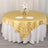 Gold striped round tablecloth on a dining table with plates and flowers.