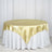 Gold satin tablecloth draped over a round table with a white underlayer.