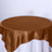 Brown satin tablecloth on a round table against a white backdrop.