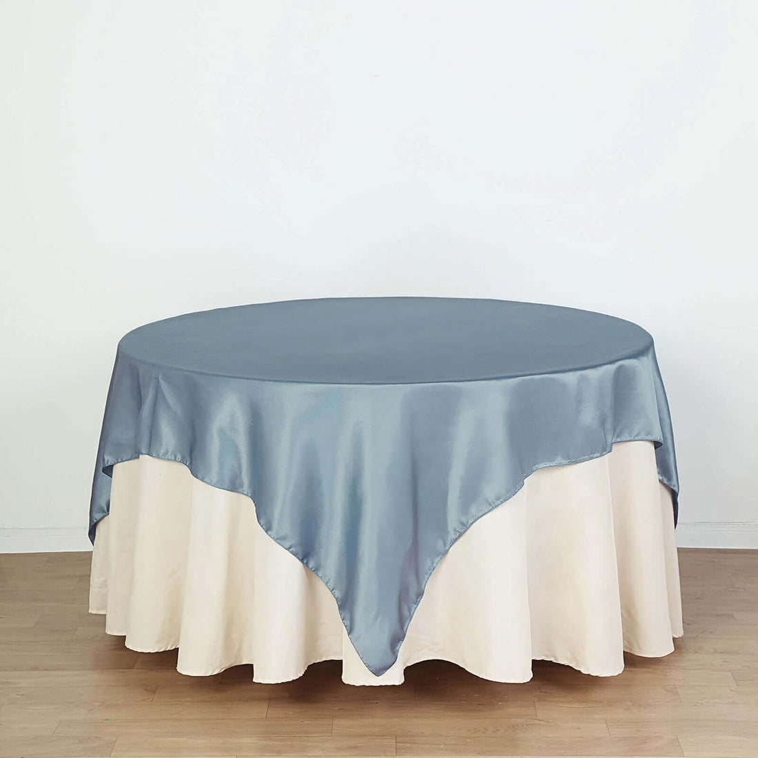 Round tablecloth with satin blue top and cream skirt on a plain background
