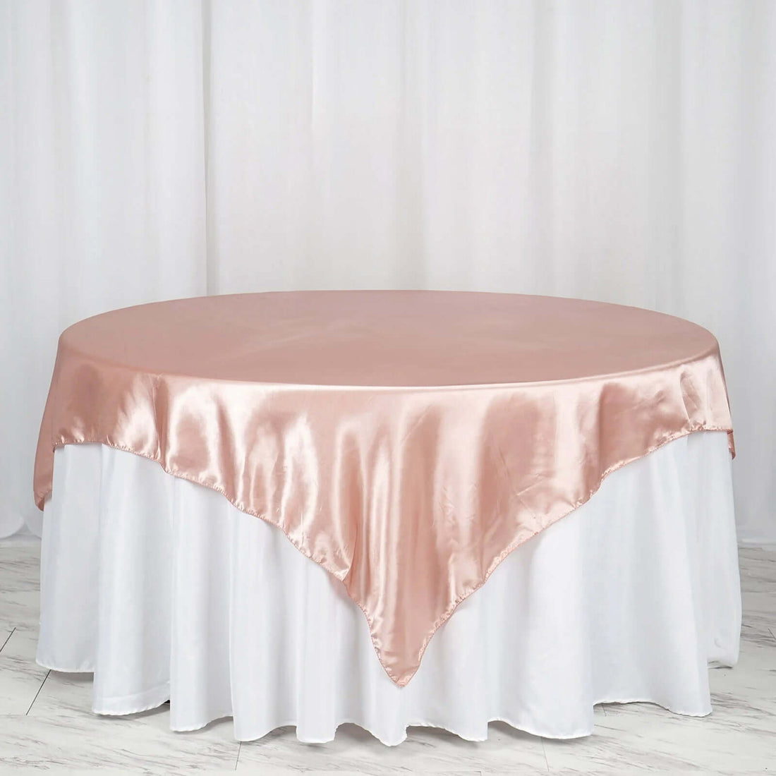 Blush satin tablecloth draping elegantly over a white table