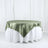 Green satin tablecloth draped over a round table in a studio setting.