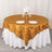 Round gold striped tablecloth on a white table with plates and flowers.