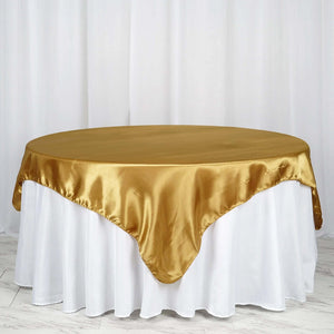 Gold satin tablecloth draped over a round table with a white skirt.