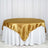 Gold satin tablecloth draped over a round table with a white skirt.