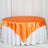 Orange satin tablecloth on a round table with a white skirt.