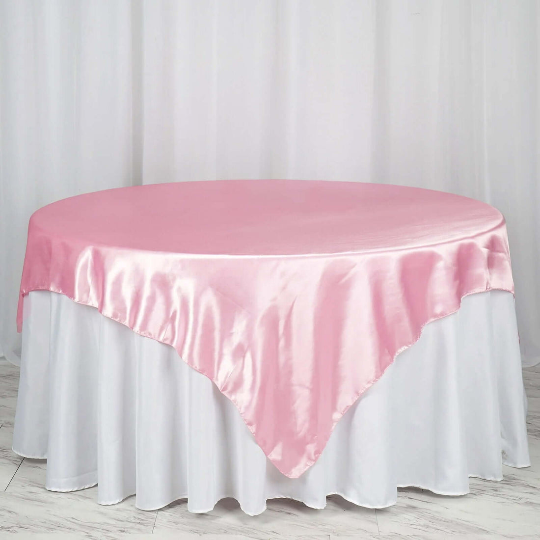 Round table with a pink satin tablecloth and white skirt