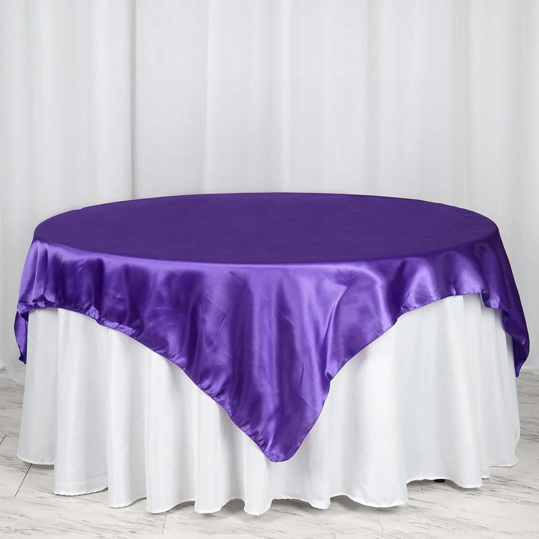 Purple satin tablecloth draped over a round table.