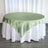 Round table with a green satin tablecloth and white skirt.
