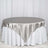 Silver satin tablecloth draped over a round table with a white skirt.