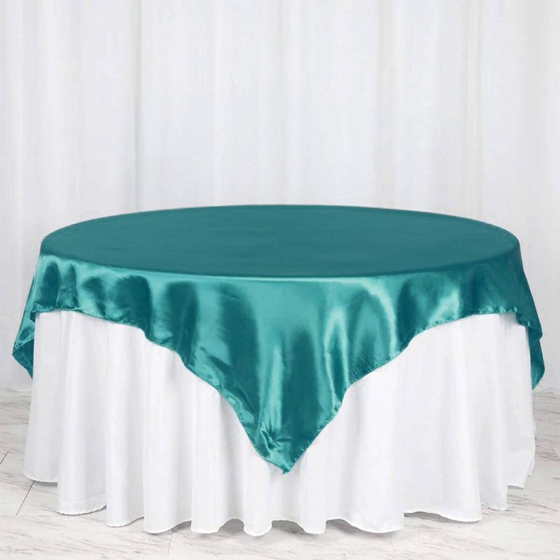 Teal satin tablecloth draped elegantly over a round table.