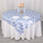 Blue floral tablecloth on a round table with plates and flowers.