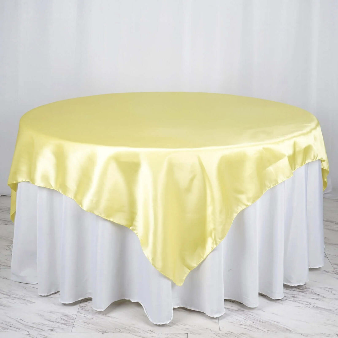 Round yellow satin tablecloth on a white table.