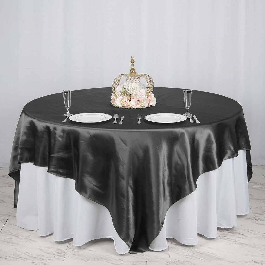 Elegant round table set with a black satin tablecloth and decorative centerpiece.