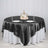 Elegant round table set with a black satin tablecloth and decorative centerpiece.