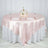 Elegant round table set with pink satin tablecloth and floral centerpiece.