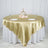 Elegant gold satin tablecloth draped over a round table with floral centerpiece.