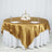 Elegant round table set with gold satin tablecloth and decorative centerpiece.
