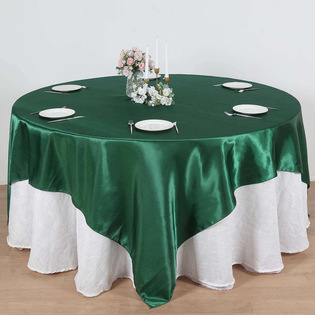 Round green satin tablecloth draped elegantly over a white table.