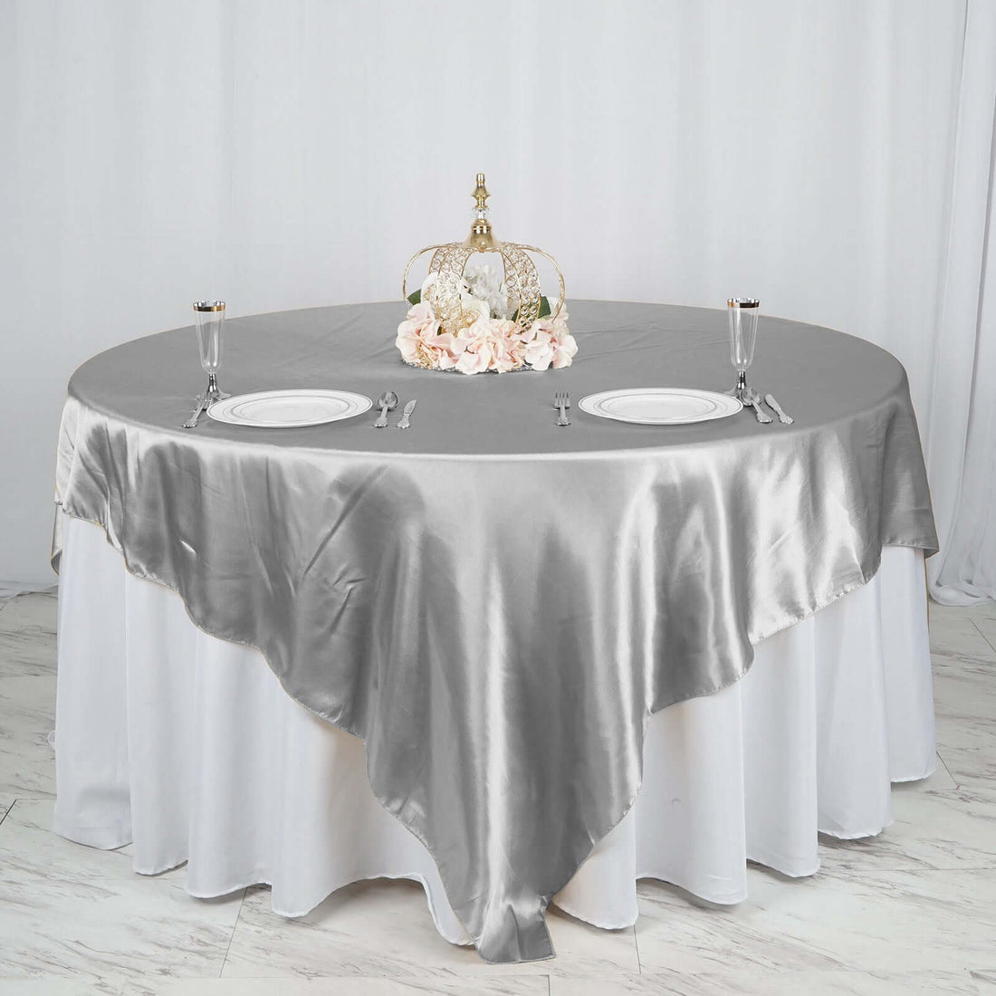 Elegant silver tablecloth draped over a round table with decorative centerpiece.