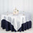 Elegant round table setup with silver and navy tablecloth, floral centerpiece, and dinnerware.