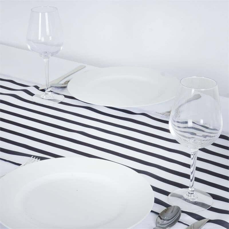 White dinner plates and wine glasses on a striped table runner.