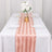 Elegant pink striped table runner on a white dining table with floral centerpiece.