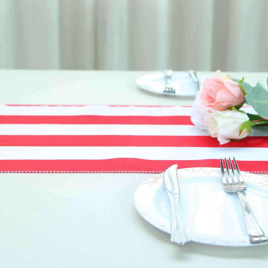 Red and white striped table runner with floral centerpiece and plates
