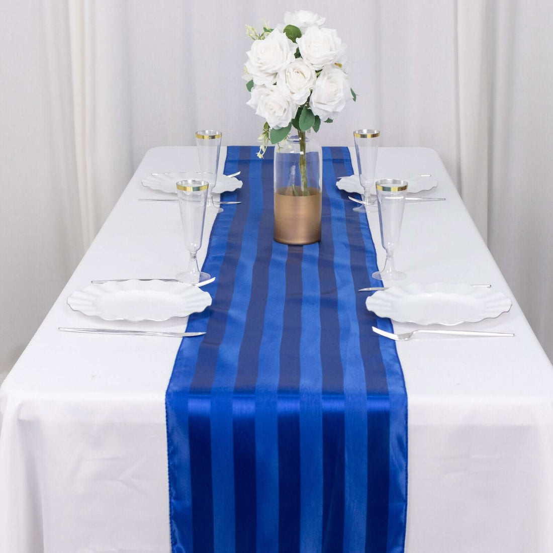 Blue striped table runner on a dining table with floral centerpiece and glassware.