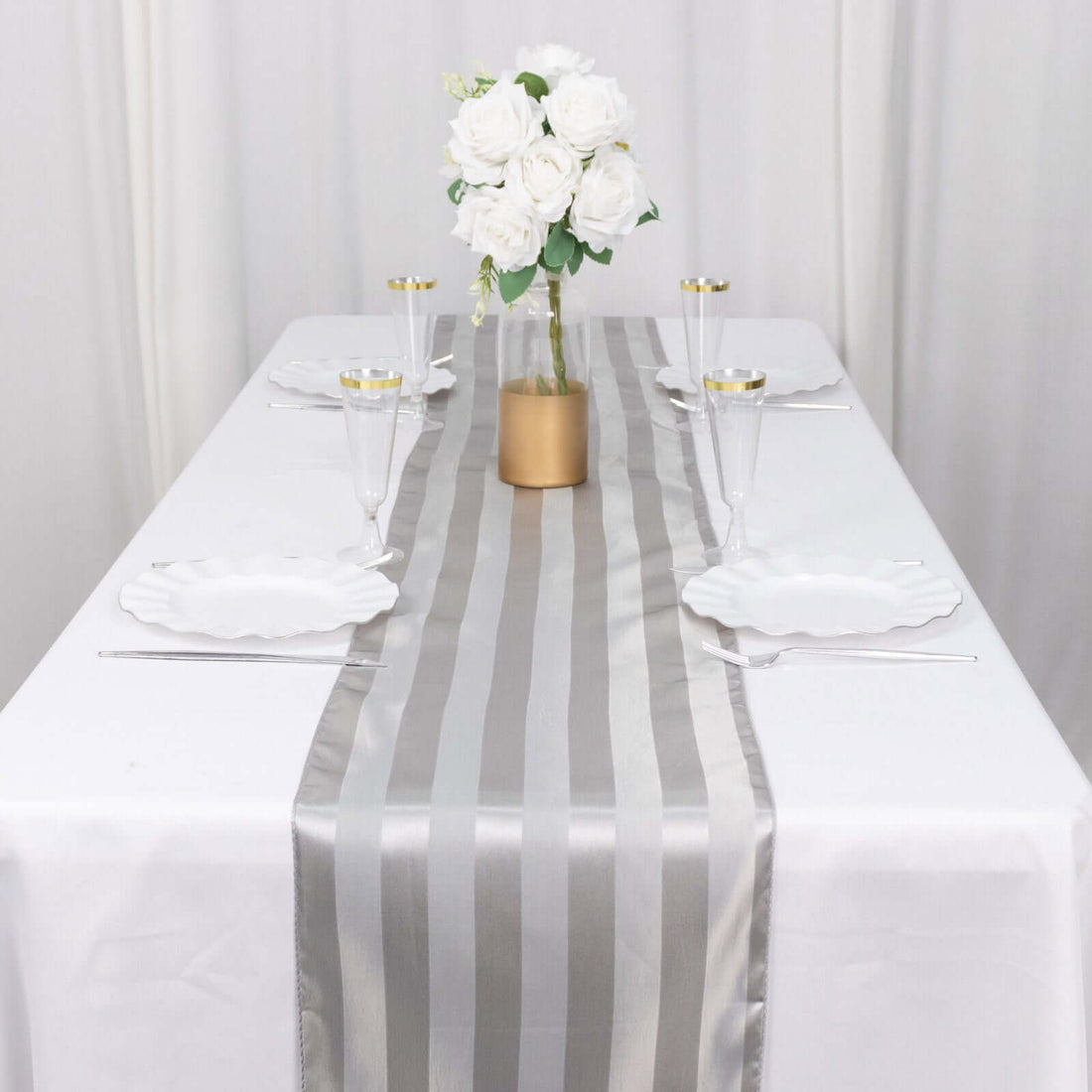 Elegant silver striped table runner on a dining table with floral centerpiece.
