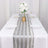 Elegant silver striped table runner on a dining table with floral centerpiece.