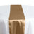 Satin table runner in gold color draped on a white table. #whtbkgd