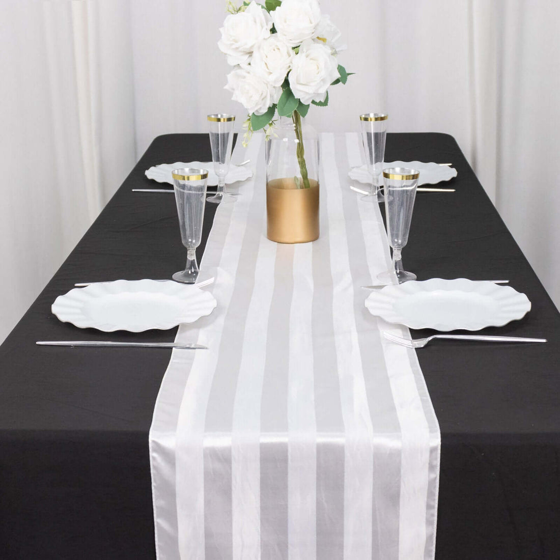 Elegant table setting with white plates, glasses, and a floral centerpiece.